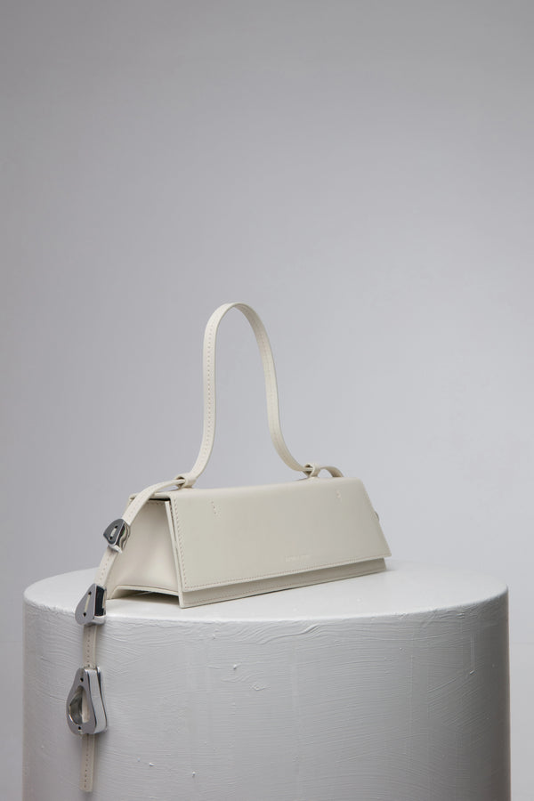 rectangular white handbag with strap on white stand